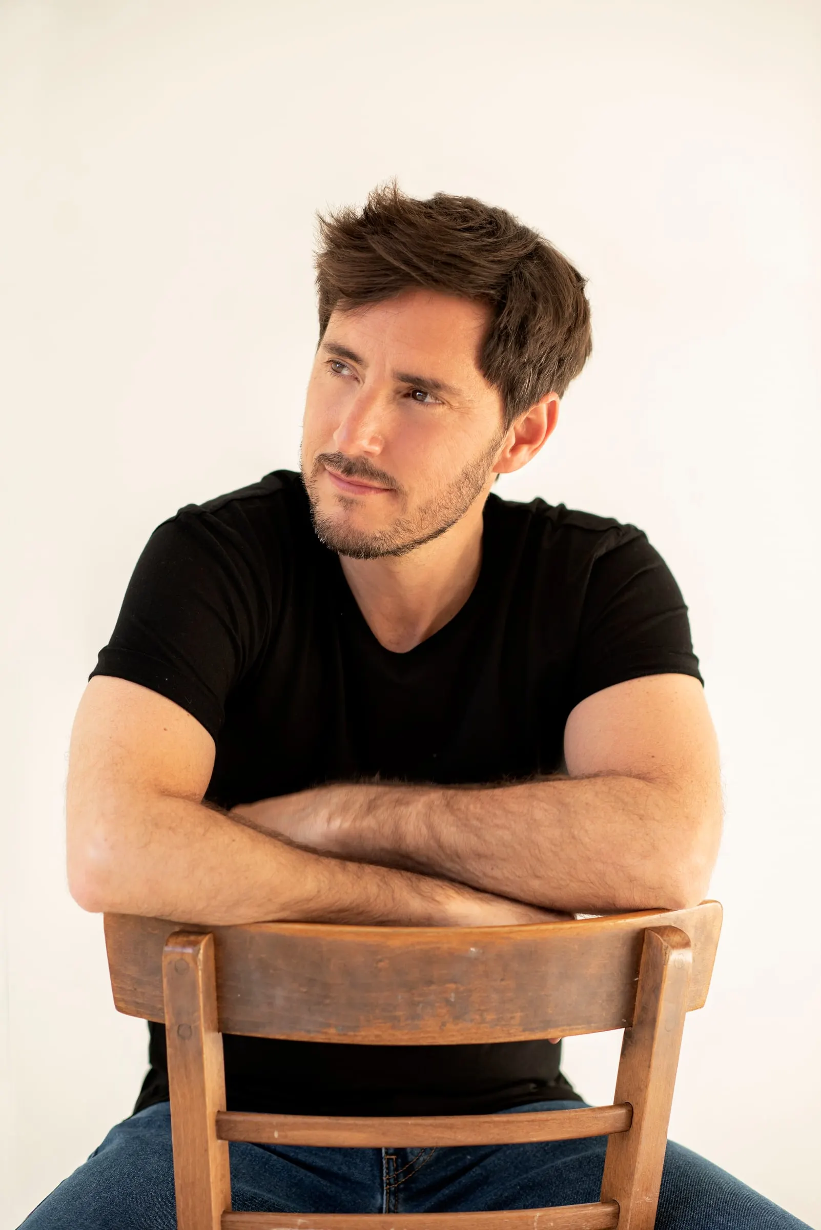 Bernardo Rivera sentado en una silla de madera con camiseta negra